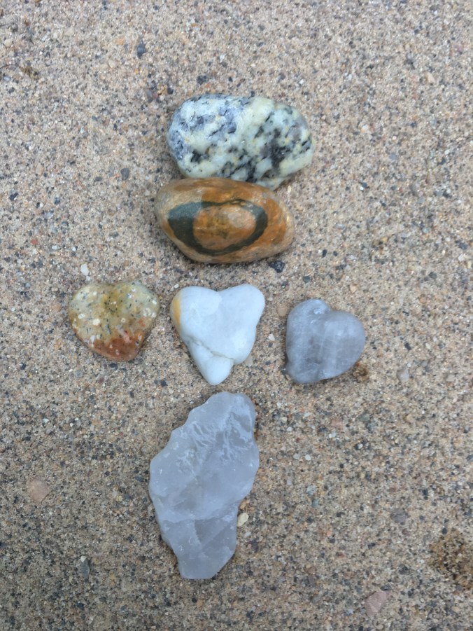 Three heart-shaped stones in the center, a stone with a heart ring above, and a footprint stone below.